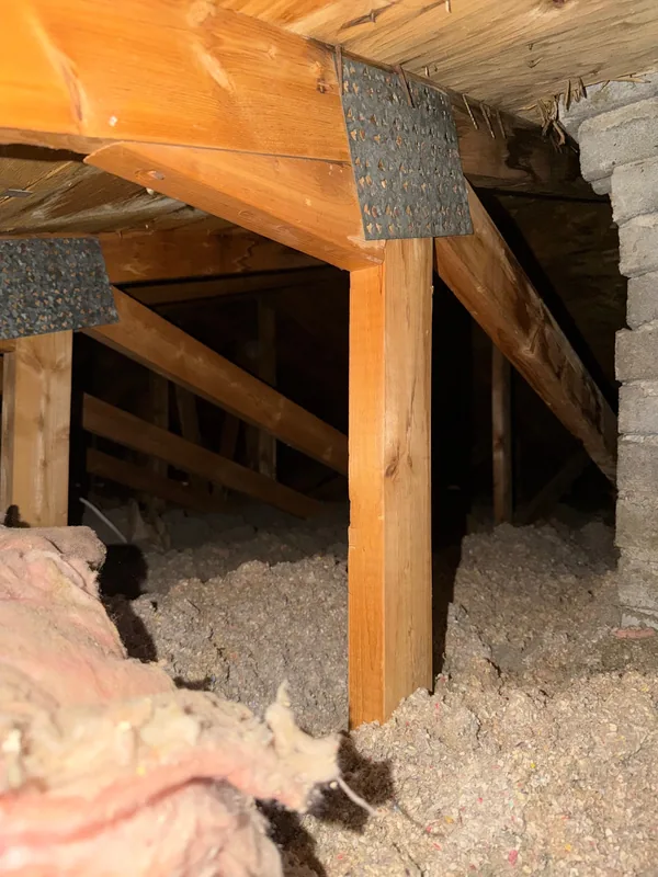 Grenier avant les travaux : vieux matelas de laine rose et isolant en vrac gris tassé autour des fermes de toit